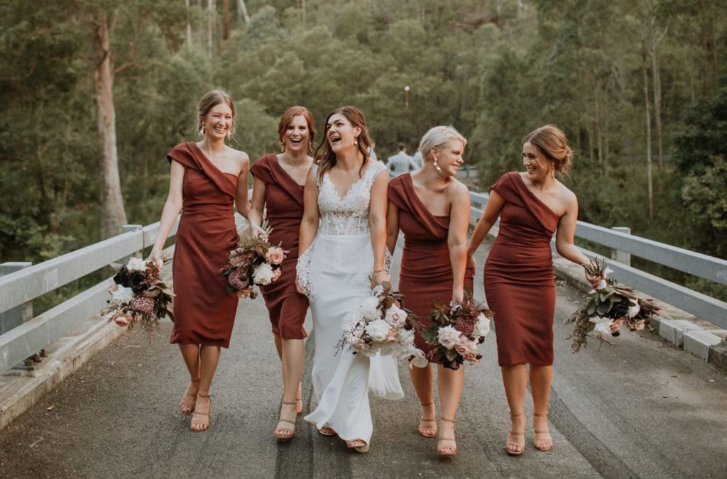 Bride in white dress with 4 bridesmaids in matching rust coloured dresses