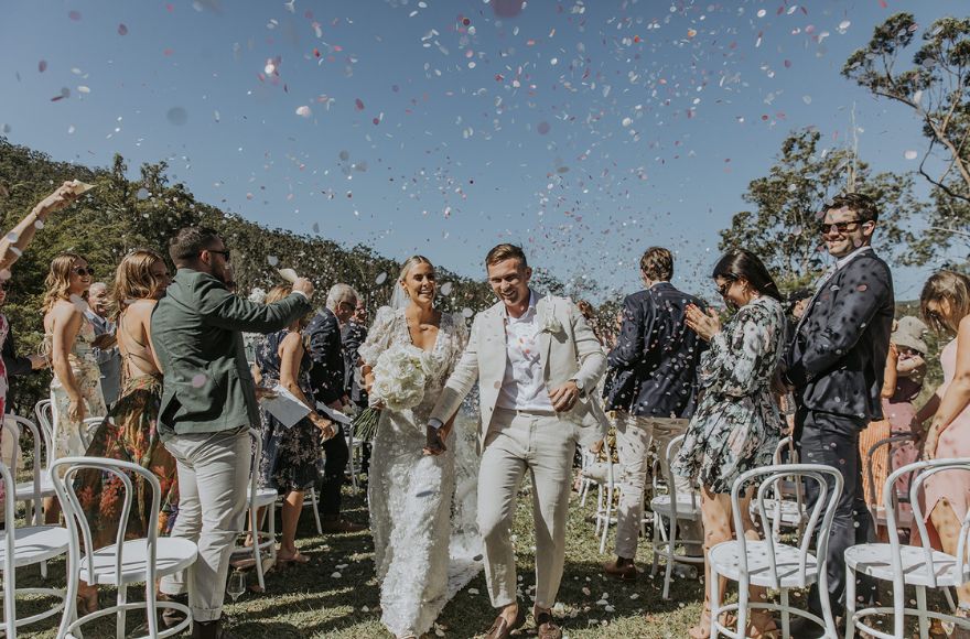 Newly married couple are showered with confetti by wedding guests