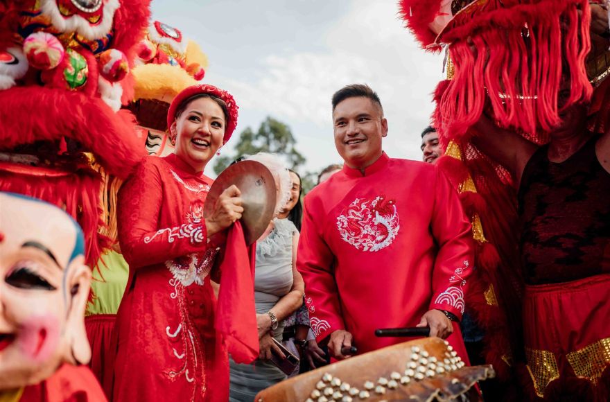Newly married couple wear red clothing surrounded by Chinese dragon dancers