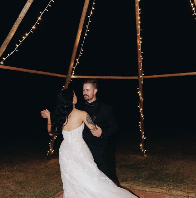 Bride and groom dance together under the naked tipi and fairly lights