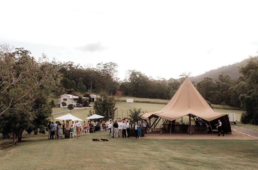Double tipi set up on the lawn with the Farm House in the background. 