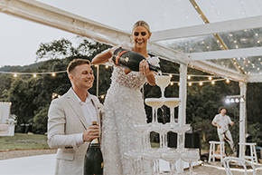couple getting at gold coast wedding reception pouring grand champagne tower under marquee