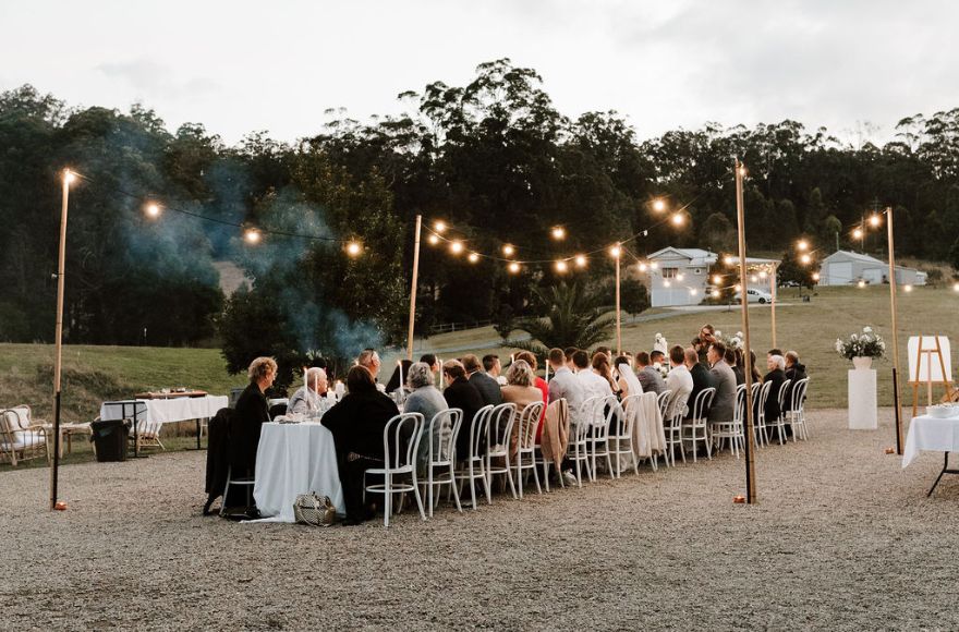 A long table in the open air seats wedding guests for an intimate reception