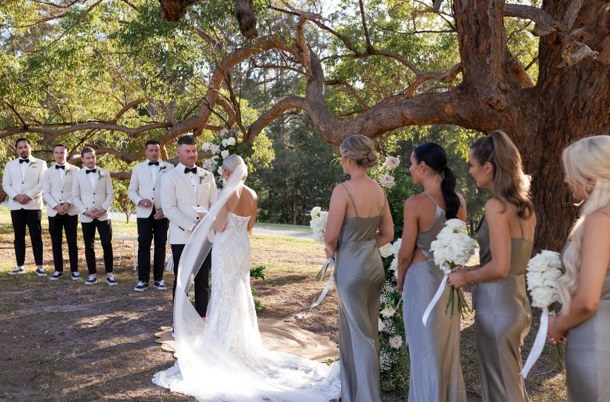 Wedding ceremony with a couple and their bridal party, held under and an acacia tree