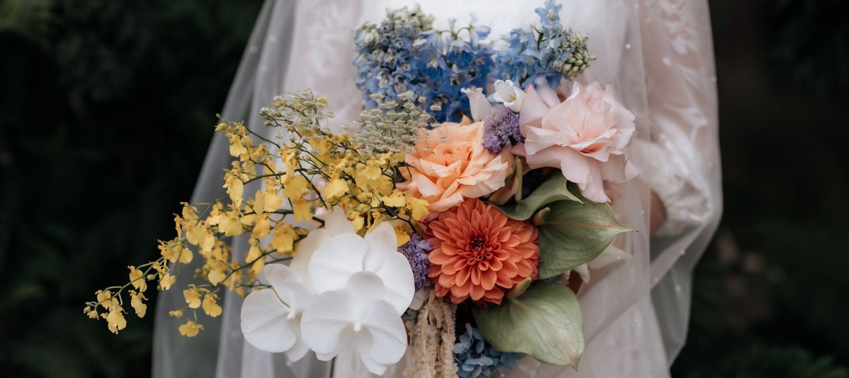 Bride holds bouquet of spring flowers in a variety of colours