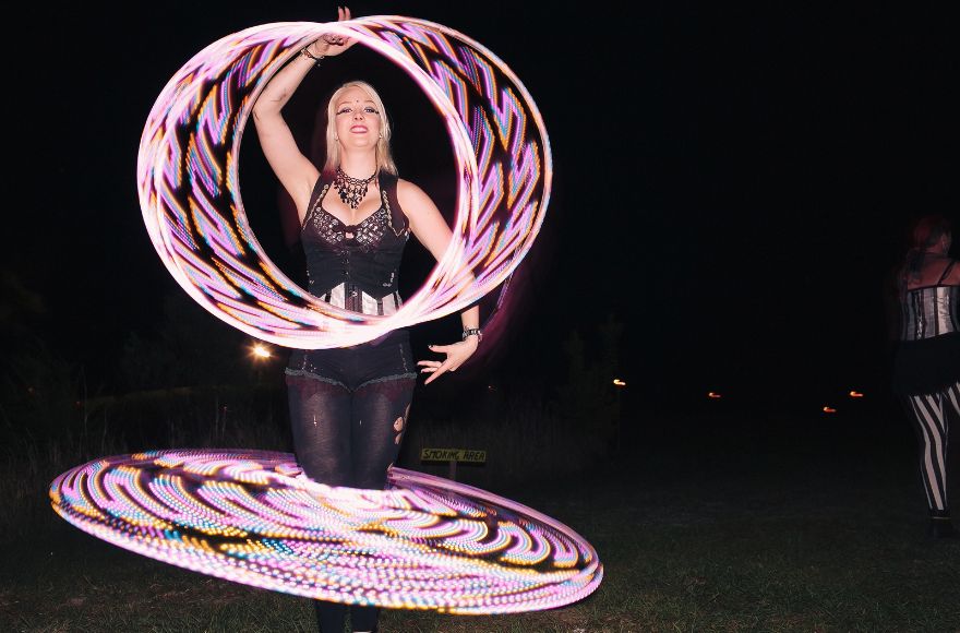 Woman entertains wedding guests with illuminated hula hoop performance. 