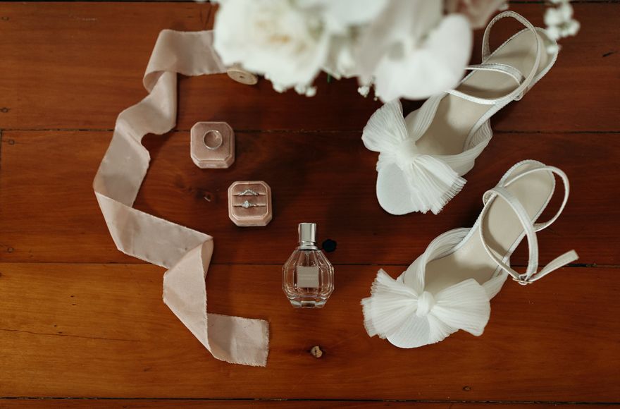 Flatlay of bridal accessories including white shoes with bows