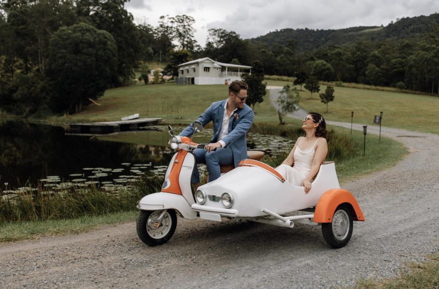Bride and groom ride on retro Lambretta motor bike with side car