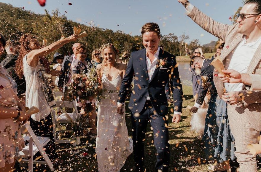 bride and groom walk up the aisle with confetti thrown at them