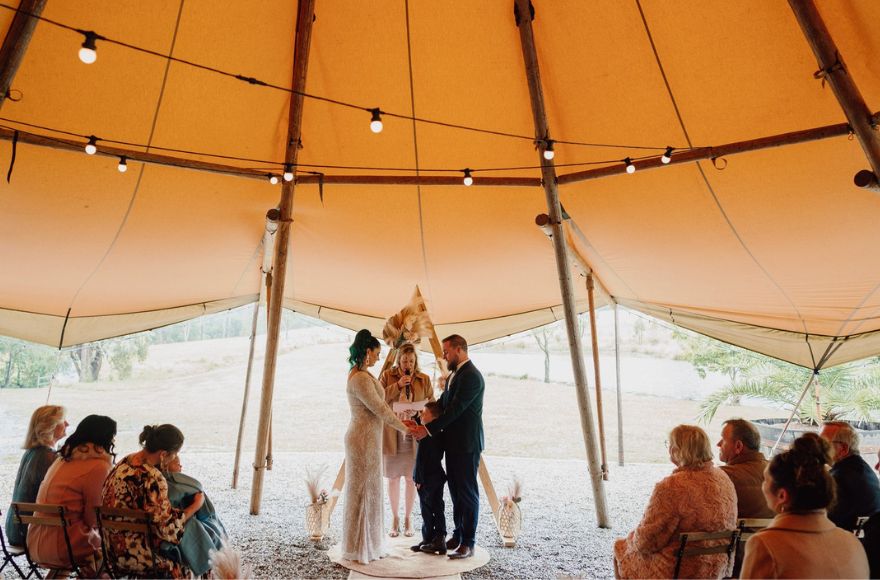 couple have their wedding ceremony under the tipi to escape the wet weather.