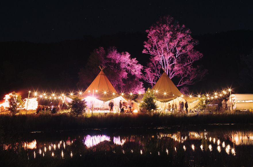 Tipis lit up for a night time outdoor wedding ceremony at the Gold Coast Farm House