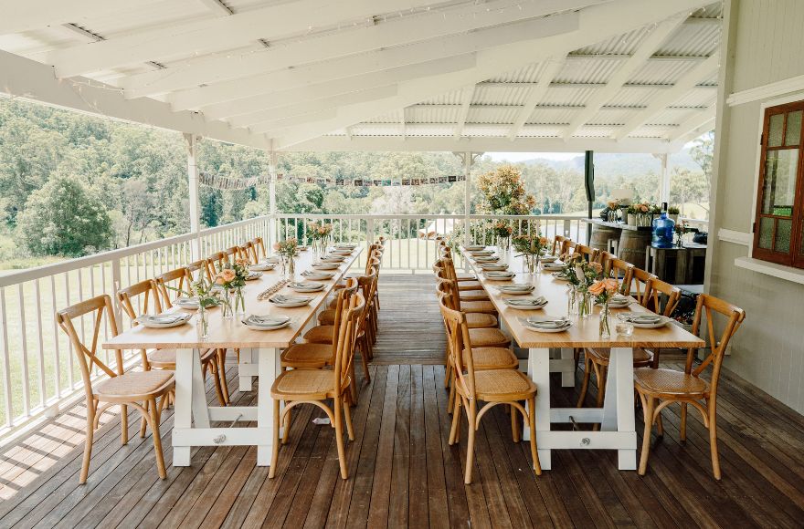 Long dining tables set up for an intimate wedding on the deck of the Gold Coast Farm House