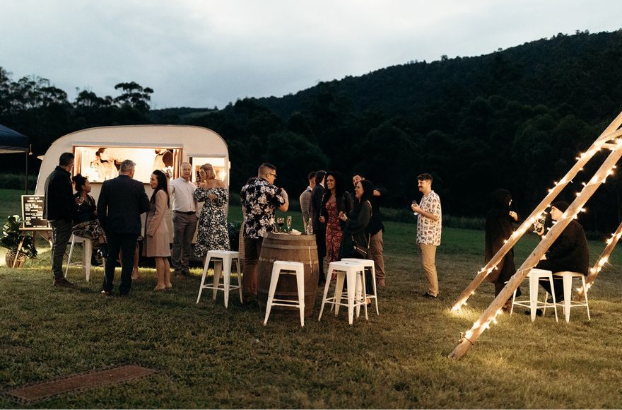 A small gathering of wedding guests mingle on the farm house property 