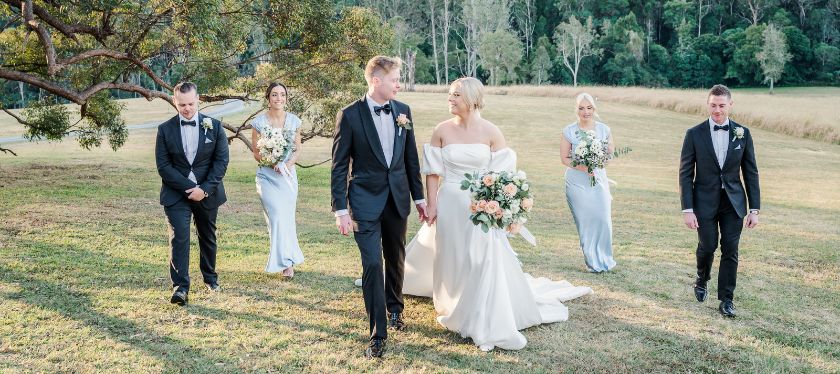 Bridal party walk on the grounds of the Gold Coast Farm House with the national park in the background